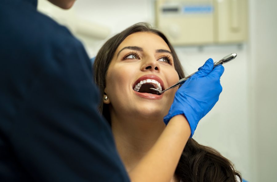 Happy, relaxed young woman in routine dental checkup Happy, relaxed young woman in routine dental checkup. Smiling while dentist holding mirror tool, closeup shot