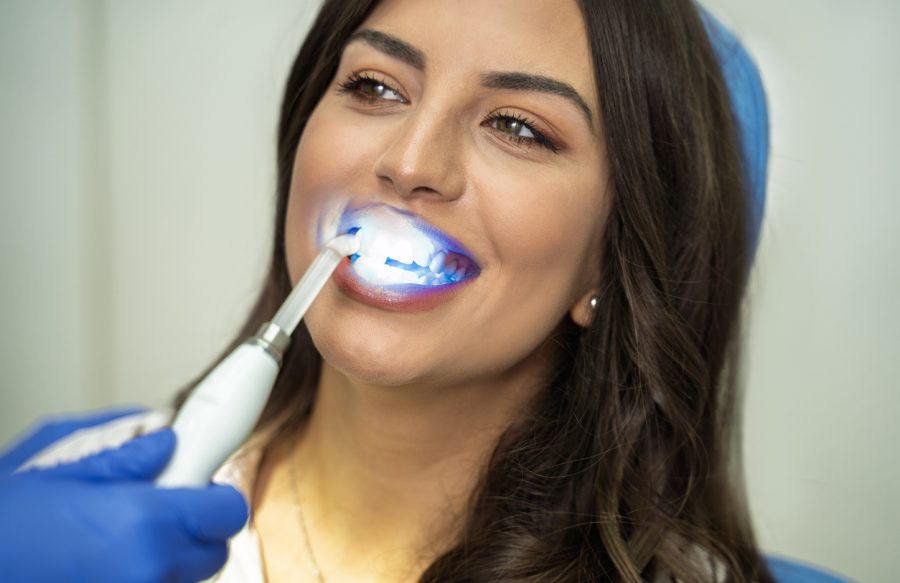 Gorgeous young woman with pretty smile having teeth whitening procedure Gorgeous young woman with pretty smile having teeth whitening procedure